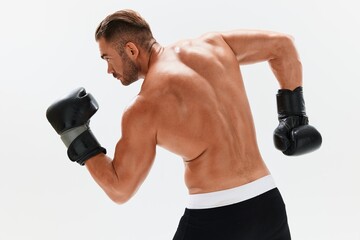 Man athletic bodybuilder poses in boxing gloves with nude torso abs in full-length background, boxing and martial arts. Advertising, sports, active lifestyle, competition, challenge concept. 