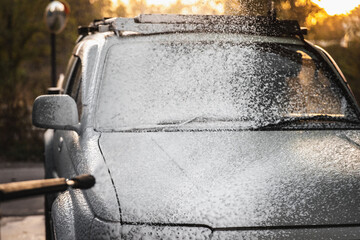 Processing with white chemical cleaning foam for washing a car from a high-pressure hose at a car...