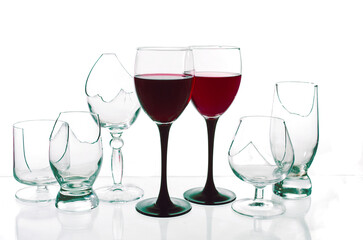Two glasses with wine on the background of empty broken glasses.