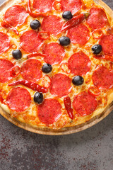 Pizza Diavola toppings with pepperoni sausage, cheese, tomato sauce, chili peppers and black olives close-up on a wooden board on the table. Vertical top view from above