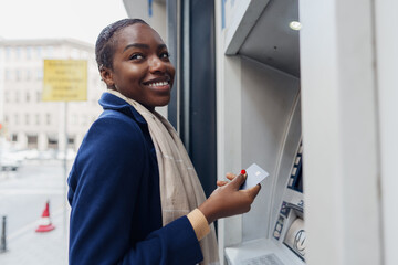 Naklejka na ściany i meble Young african woman withdrawing cash at the ATM