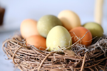 Close-up of a nest of twigs inside with yellow, green and light green easter eggs