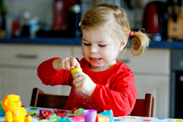 Adorable cute little toddler girl with colorful clay. Healthy baby child playing and creating toys...