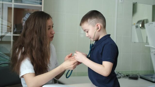 a boy listens to how a stethoscope works at a doctor's appointment