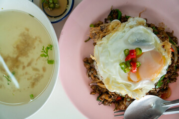 Stir fried Thai basil with minced pork and a fried egg on white plate