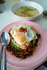 Stir fried Thai basil with minced pork and a fried egg on white plate