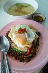 Stir fried Thai basil with minced pork and a fried egg on white plate