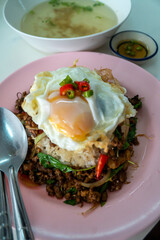 Stir fried Thai basil with minced pork and a fried egg on white plate