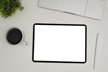 Top view of a modern workspace with digital tablet white screen mockup, stylus pen, laptop