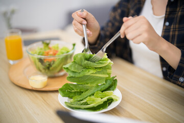 Happy beautiful Asian woman eating healthy food with vegan.salad in the kitchen at home.