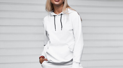 Design mock-up for clothing logo. A woman wears a white hoodie on the street.