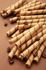 Coffee wafer stick roll with coffee cream on brown background. Vertical photo