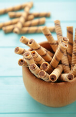 Coffee wafer stick roll with coffee cream in bowl on blue background.