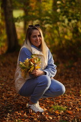 Young caucasian woman resting carefree, relaxing on lawn on sunny day. Side view hipster woman enjoying calmness and freedom during coffee break while sitting on grass outdoors