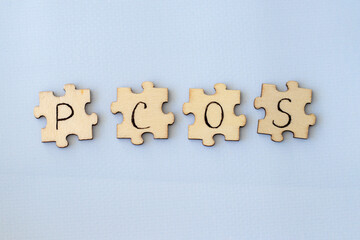 Polycystic Ovarian Syndrome. Hand Writing PCOS on wooden puzzles on a blue background