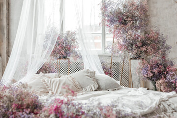 A bed in a bright bedroom in pastel colors in boho style, the trending color of 2023. The room is...