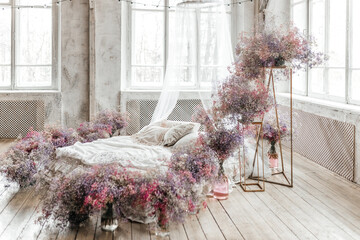 A bed in a bright bedroom in pastel colors in boho style, the trending color of 2023. The room is...