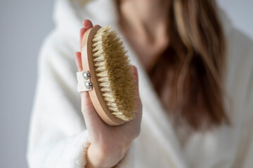 Body brush for dry massage in women's hands. Brushing body to reduce cellulite, detoxify the...