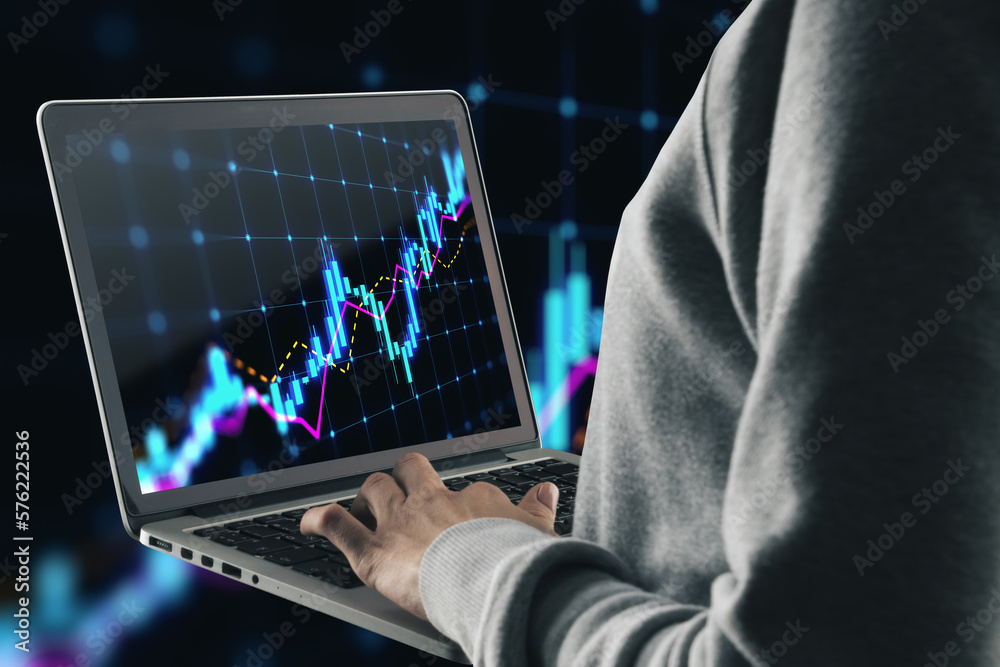 Poster close up of hands using laptop with glowing candlestick forex chart hologram on blurry dark backgrou