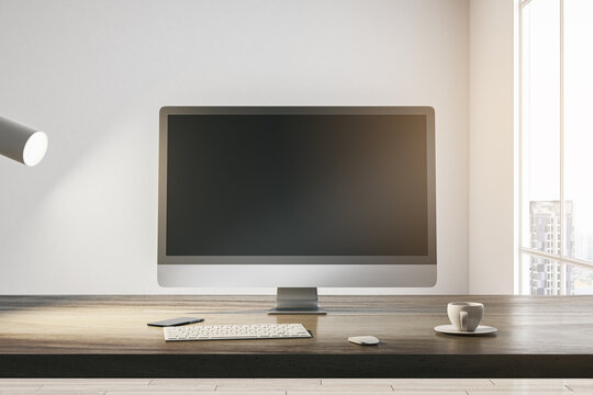 Front view on blank dark modern computer monitor with place for your web site or web design on wooden table with coffee cup and keyboard on light wall background in sunlit room. 3D rendering, mock up