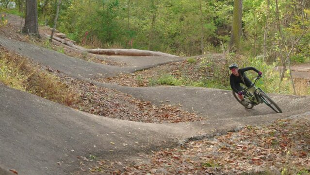 A woman (charlotte batty) riding mountain bike berms made out of asphalt in bentonville arkansas on her santa cruz ebike.