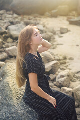 Beautiful young model girl posing at the tropical beach in long black dress having joy on the summer wind