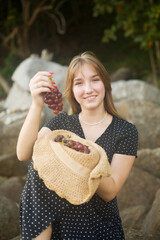 Beautiful young girl ready to eat grape on the beach bring fresh fruit harvest for picnic