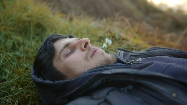 Relaxing in the Heart of Nature: Handsome Young Man Taking a Deep Breath and Resting Amidst the Grasslands