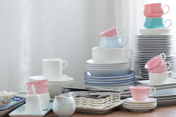 pink, white abd blue  cutlery on a wooden table against a white wall