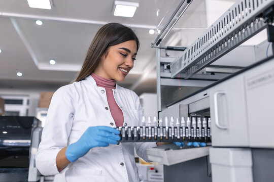Female Research Scientist Holds Test Tubes with Blood Samples before Puting them into Analyzer Medical Machine. Scientist Works with Modern Medical Equipment in Pharmaceutical Laboratory.