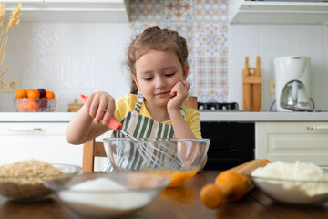 child helping in kitchen. kid cooking food. little cute girl in apron in preparing dough, baking pie, cookies, making biscuit. family together at home.