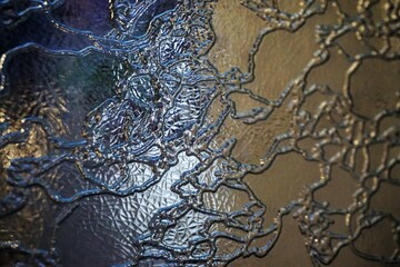 Goldgelb-blaue Glasfassade mit Wellenmuster und Licht als Hintergrund 