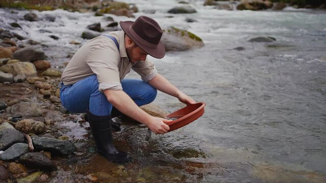 man in the hat Panning for gold in a creek bed Panning mining and extraction in river,Finding gold