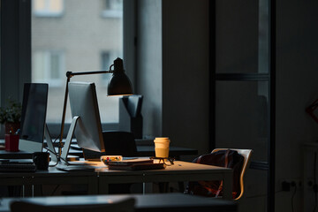 Horizontal image of workplace of programmer with computer on table in dark office