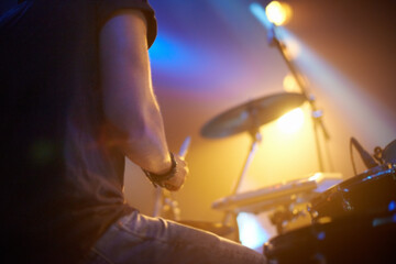 Smacking the skins hard. A young drummer rocking out on stage.