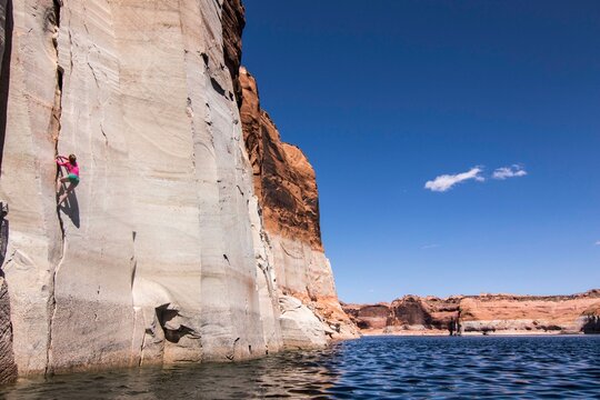 Woman rock climbing up cliff, Lake Powell, Utah, USA