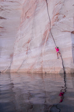 Woman rock climbing up cliff, Lake Powell, Utah, USA