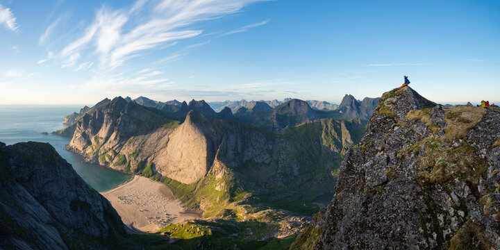 Hiker looking at view of Bunes beach from mountain peak, Moskenesoya, Lofoten Islands, Norway