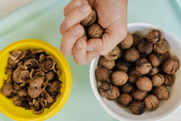 Two bowls filled with whole walnuts and nutyshells and male hand holding nuts