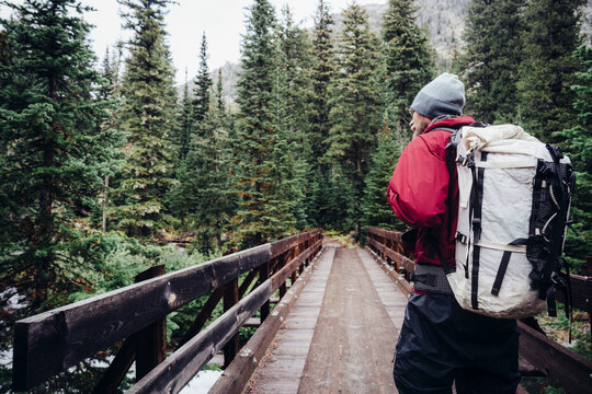 Male Hiker Crossing Bridge In Forest