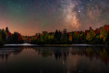 Milky way over river and autumn colored trees