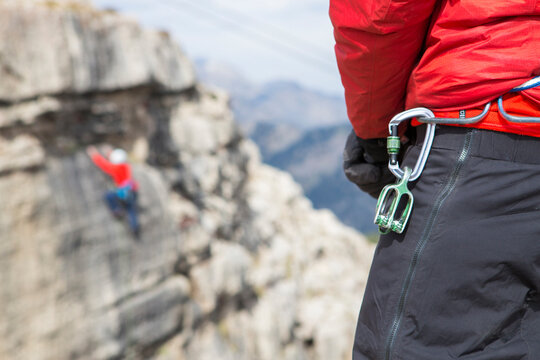 Close up of carabiner hanging from belt of climber watching friend ascend Rendezvous Peak, Wyoming, USA