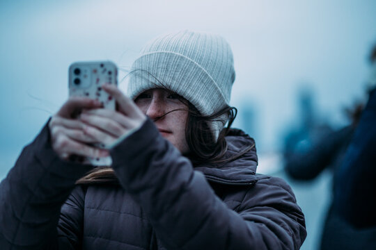 Teen girl taking a photo on a cold day