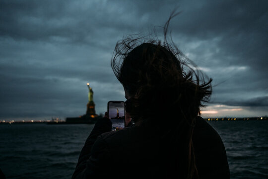 Woman taking a photo of Statue of Liberty on mobile phone