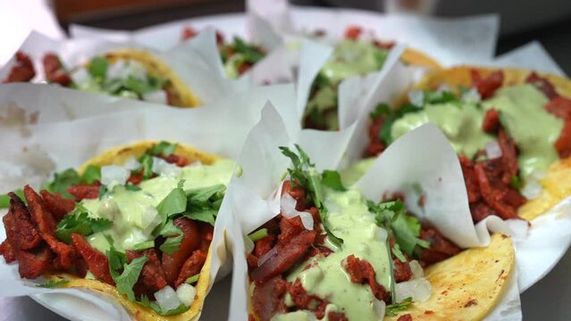Slow motion savory look at street tacos with guacamole sauce on a plate - food truck series