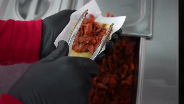 Filling a corn tortilla with pork for street tacos - food truck series