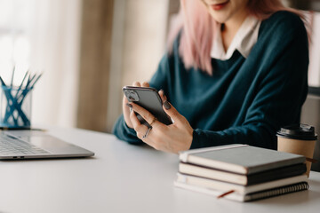 Young beautiful woman typing on tablet and laptop while sitting at the working wooden table modern office.