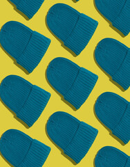 Demi-season blue ribbed knitted hat pattern background. Winter new stylish knitted wool headwear blue hat on yellow.