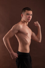 Fototapeta premium Handsome muscular shirtless adolescent boy flexing muscles.