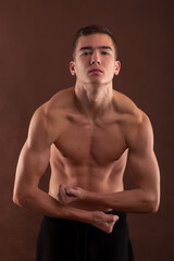 Fototapeta na wymiar Handsome muscular shirtless adolescent boy flexing muscles.